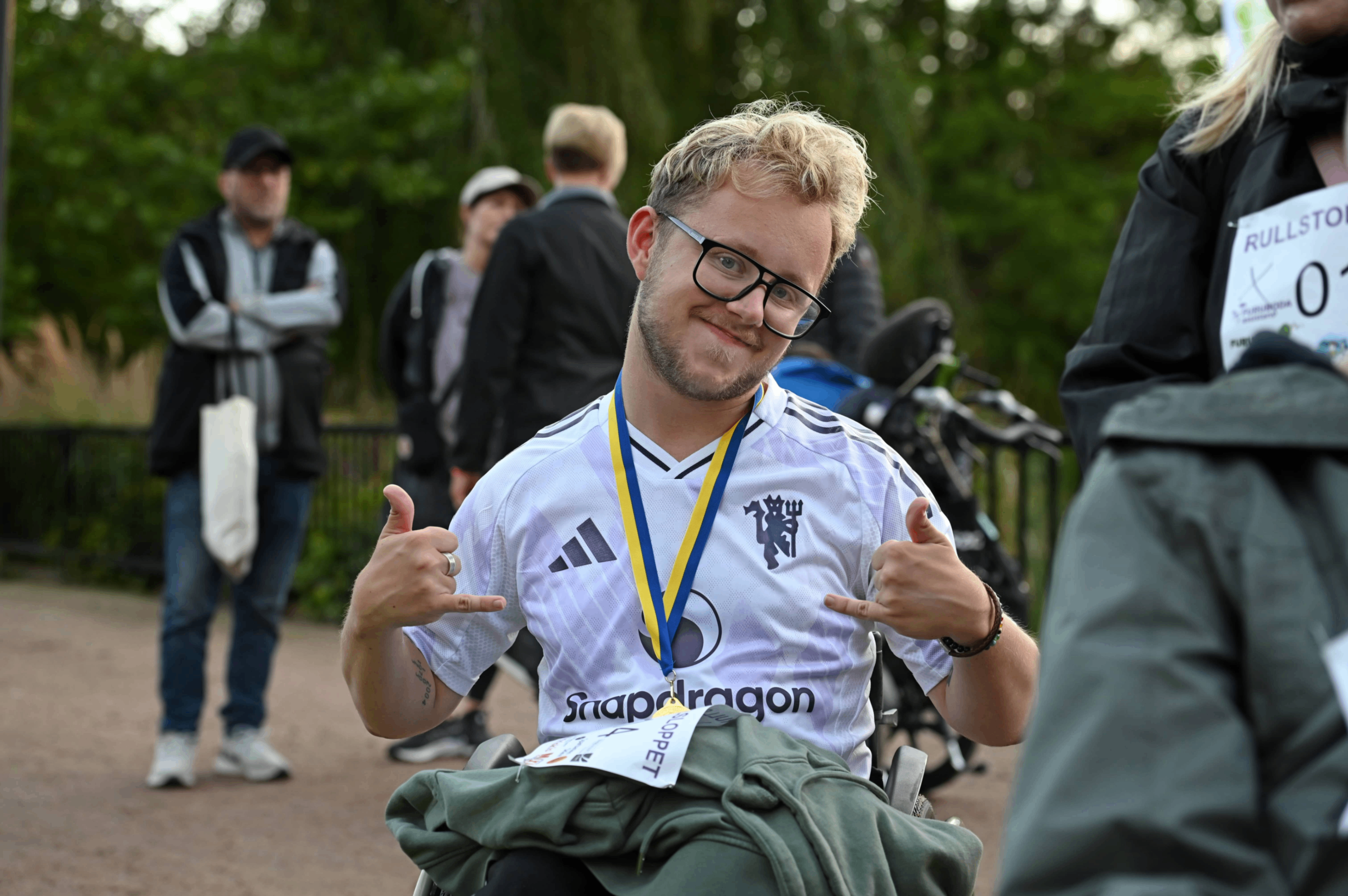 En kille med medalj runt sin hals, har deltagit i Rullstolsloppet