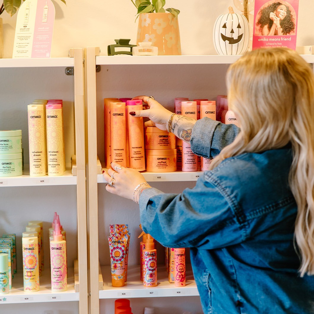 photo of blonde client reaching for an amika hair product on the shelf
