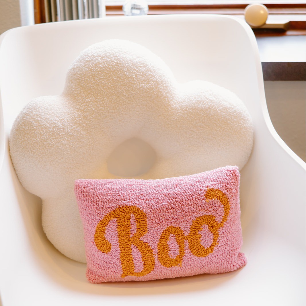 Book pillow in front of flower pillow on chair in sittinyg area of salon