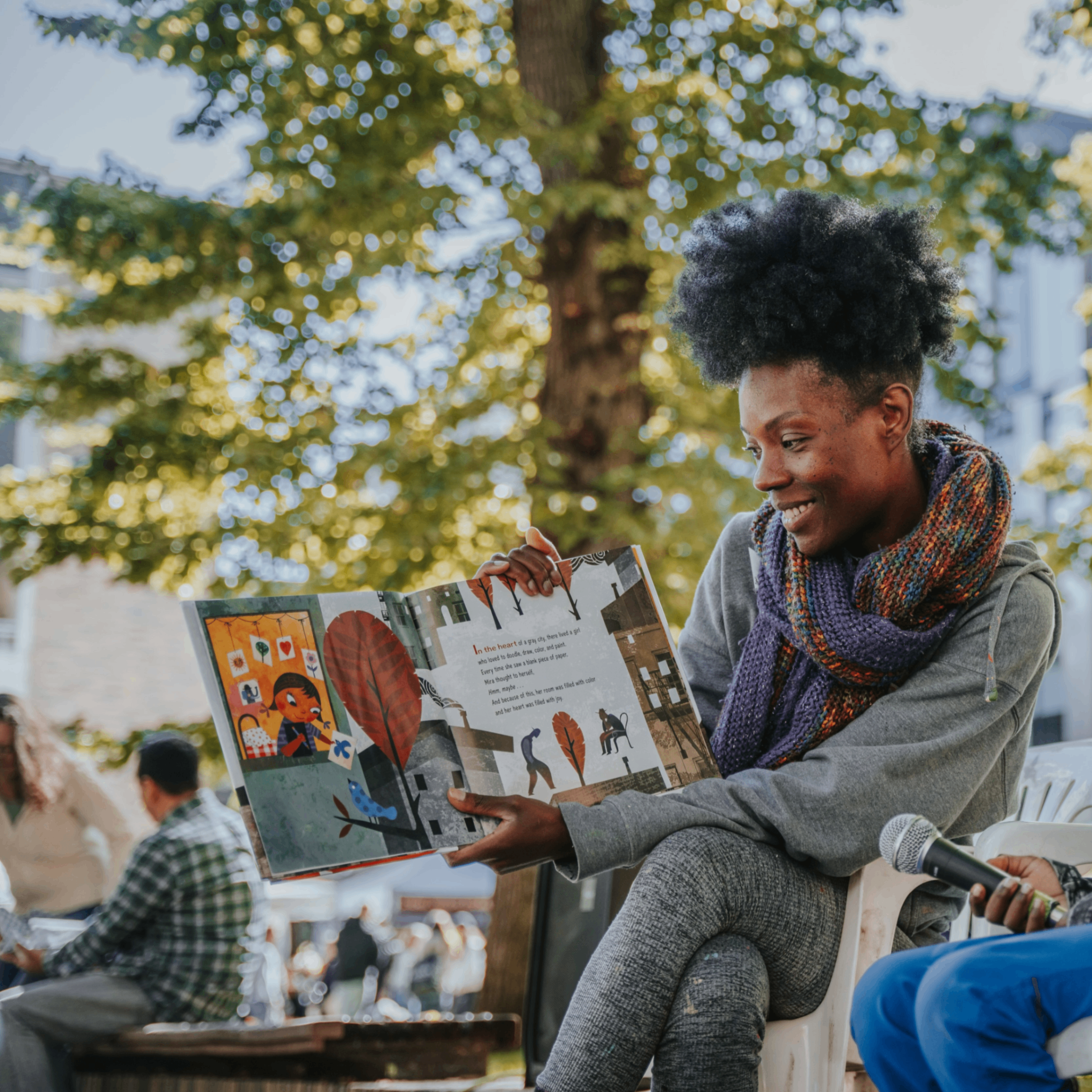 A woman reads a children's storybook outside in a farmers market