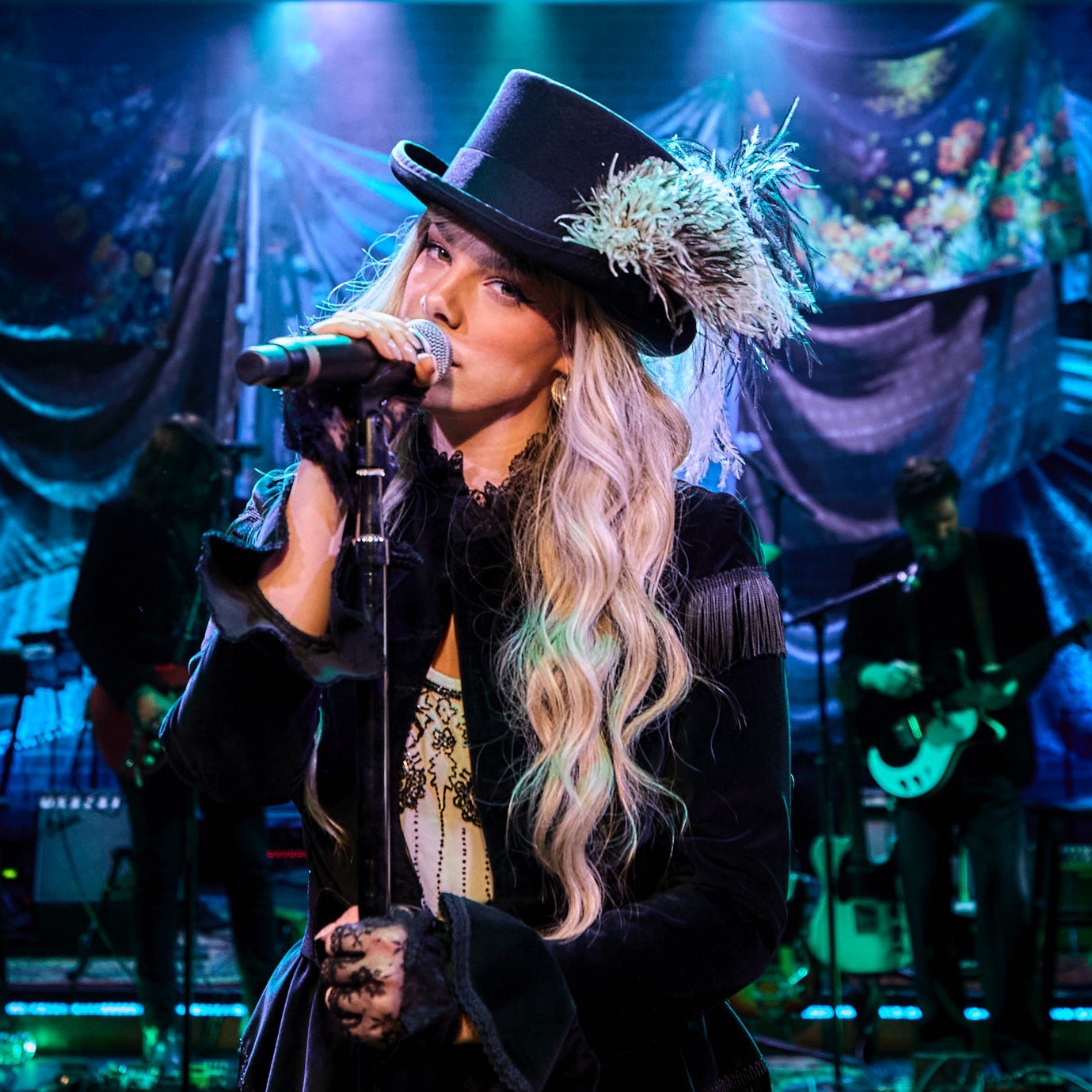 a woman with a hat on sings into a microphone