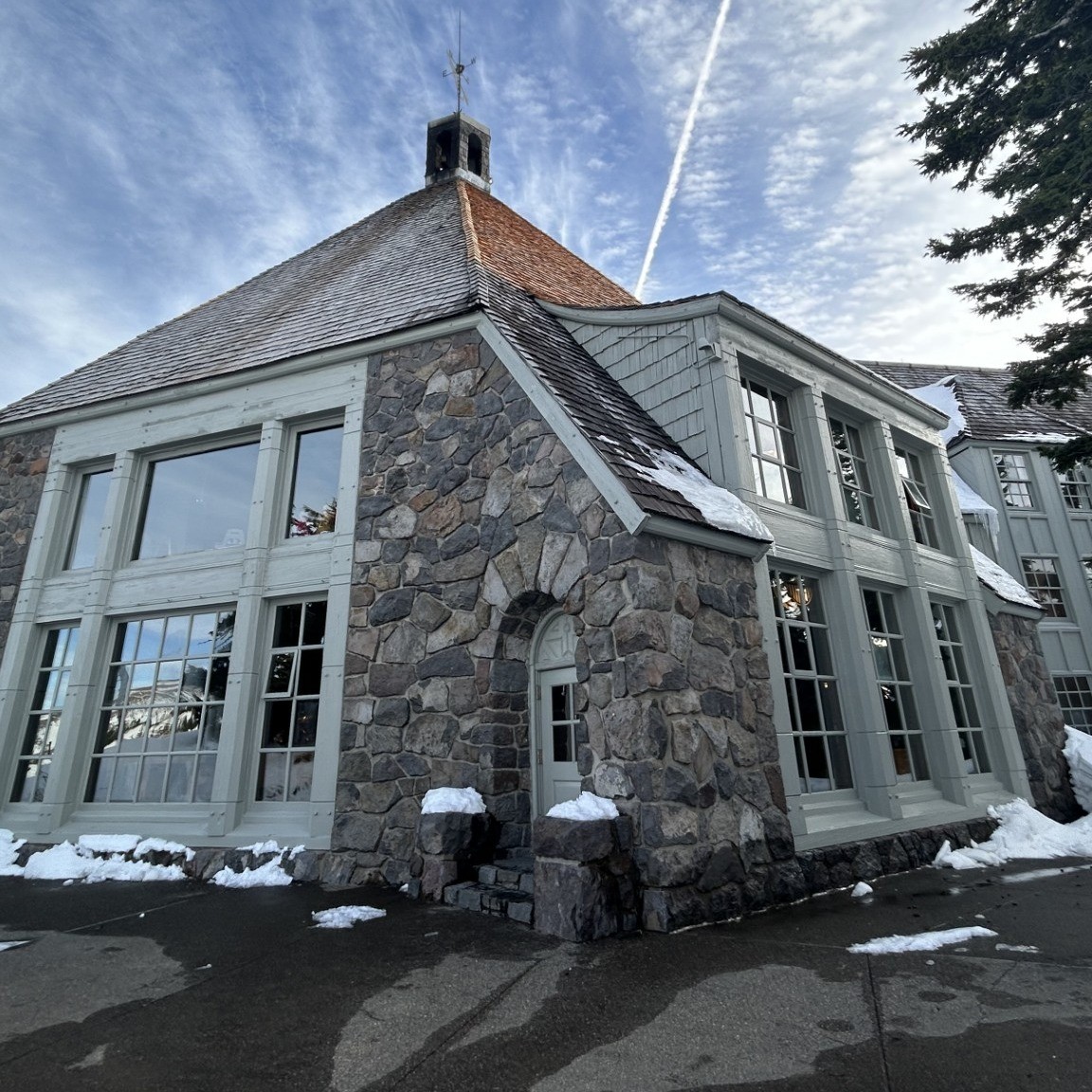 a stone sidded building with large pane glass windows
