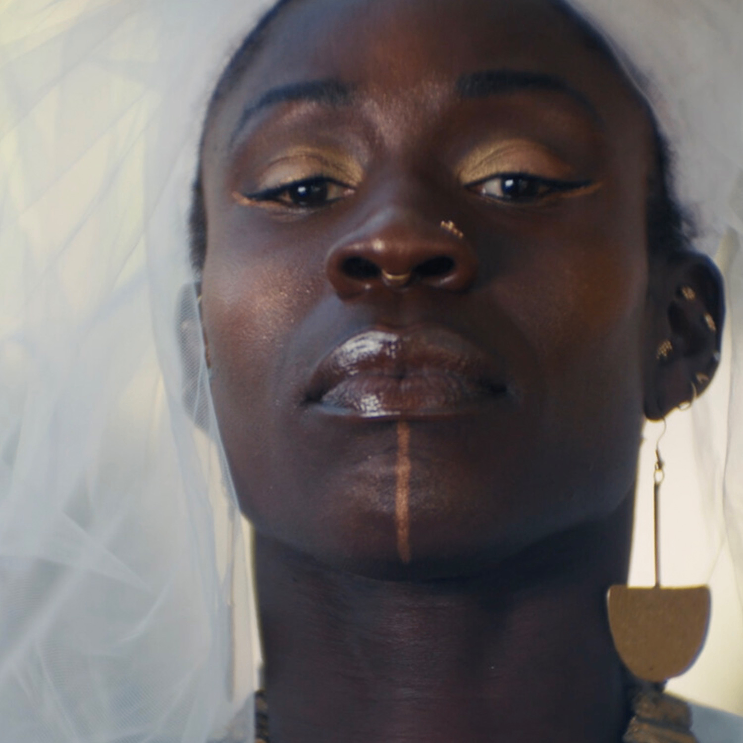 A white bridal veil surrounds the head of Black bride with makeup inspired by ancestral traditions.