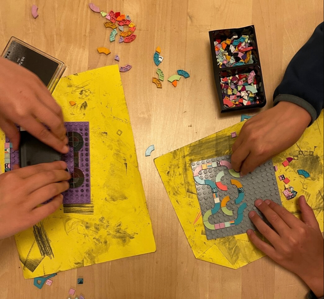 Bilden visar en närbild på händer som bygger med lego