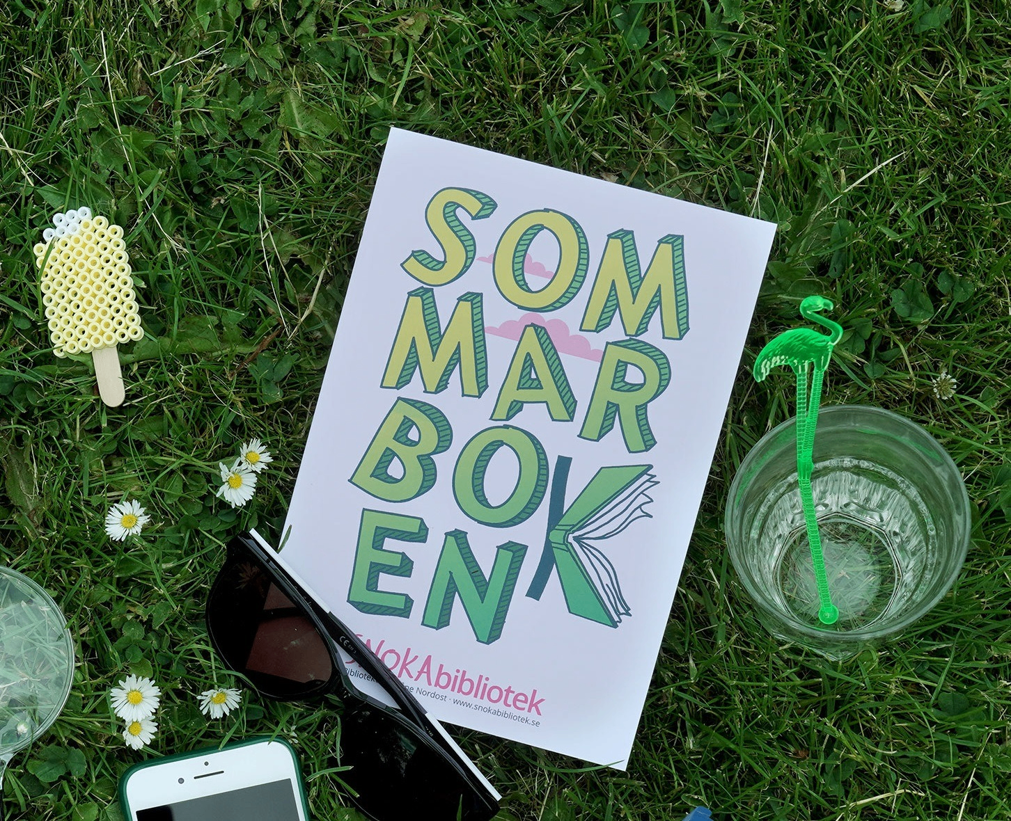 Ett sommarboken häfte ligger på en gräsmatta.