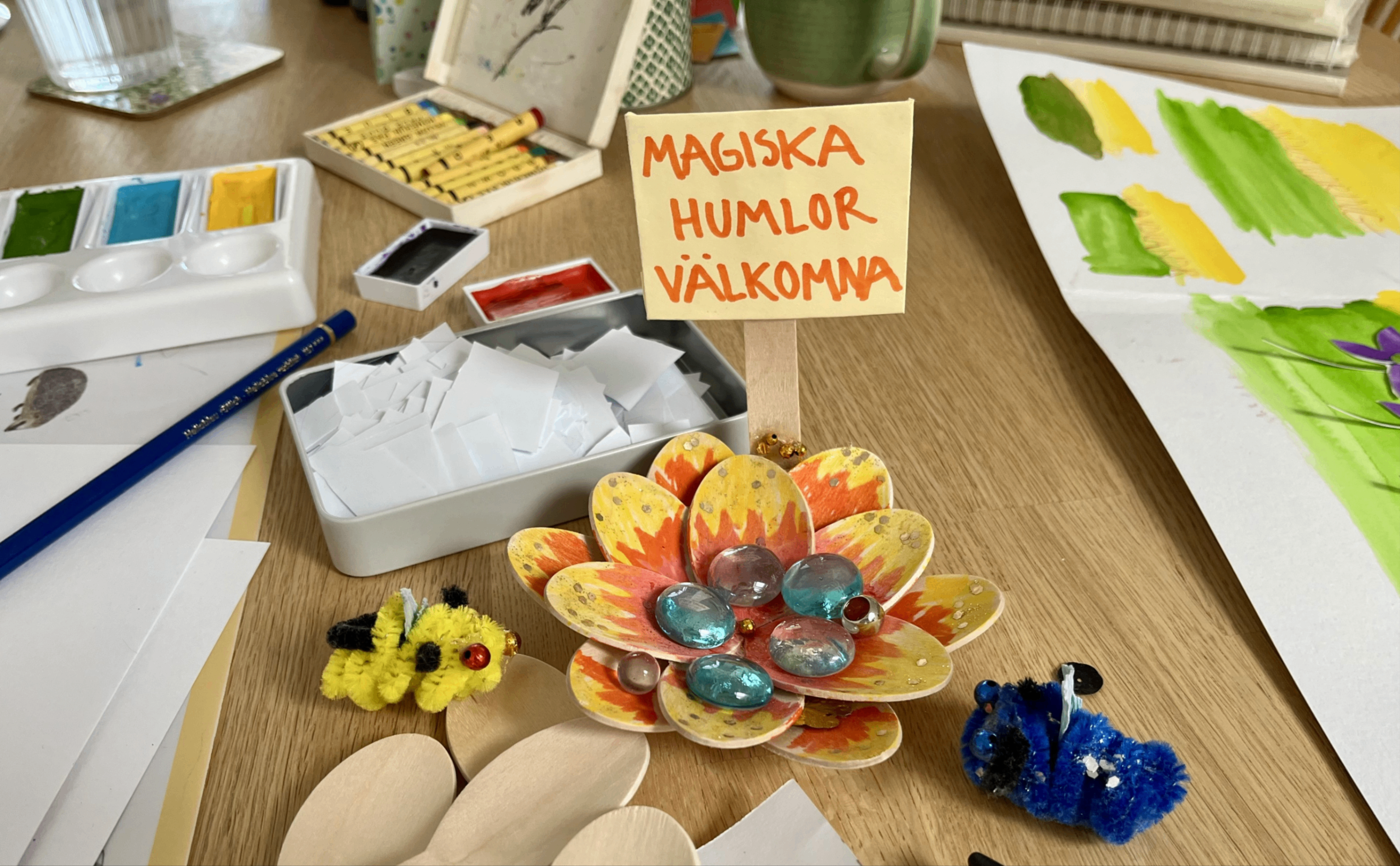 Målarfärg, färgpennor och pysselgrejer på ett bord