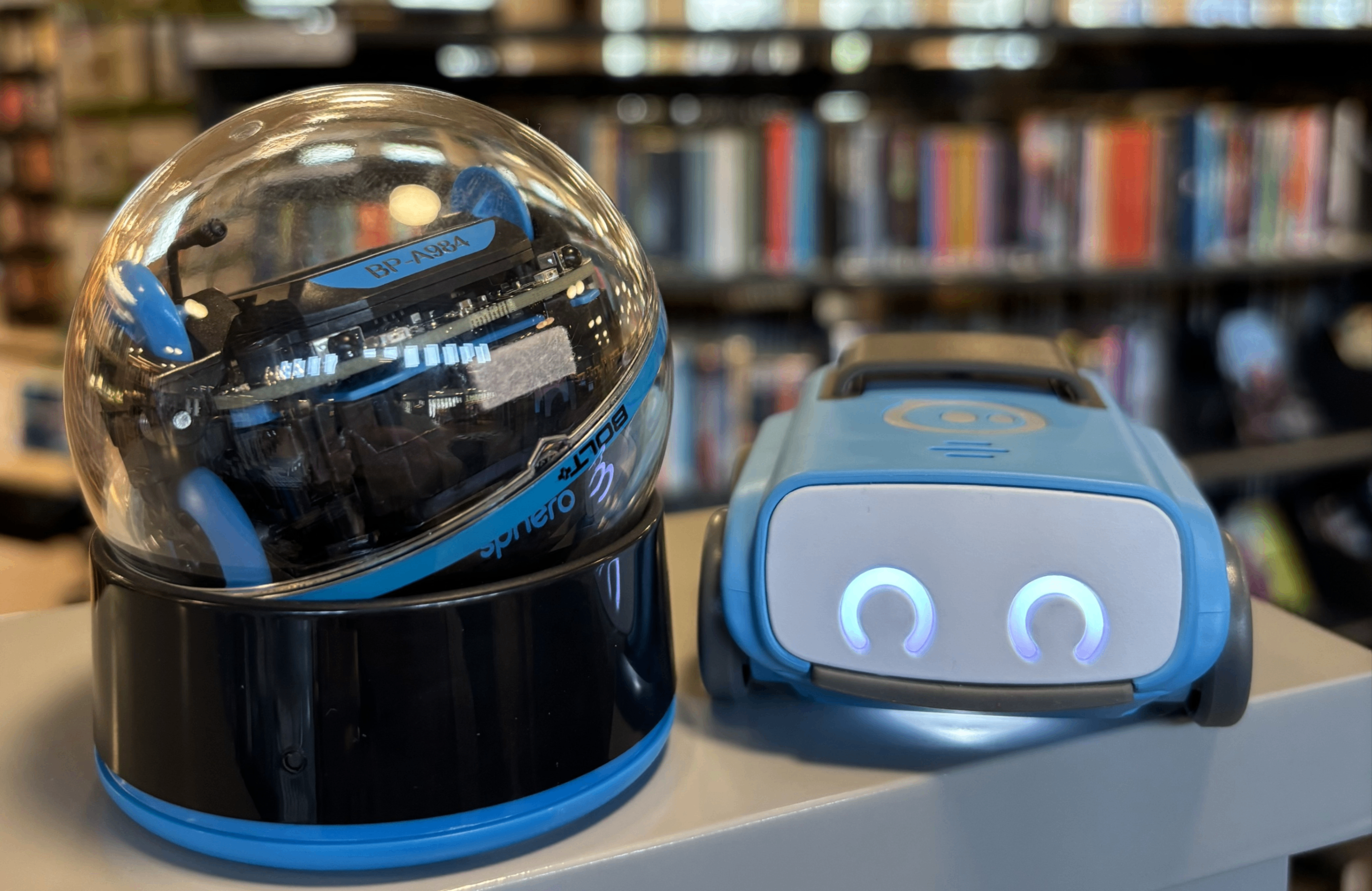 Två robotar framför bokhyllor.