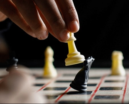 Bilden visar en närbild på en hand som flyttar en schackpjäs