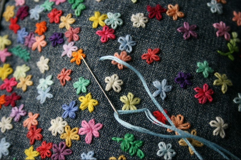 Broderade blommor, nål och tråd.