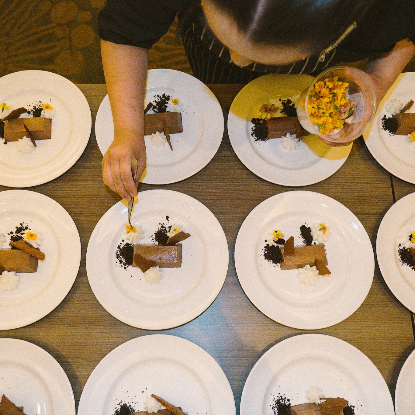 Celebration of Cacao desserts being plated and garnished with edible flowers.