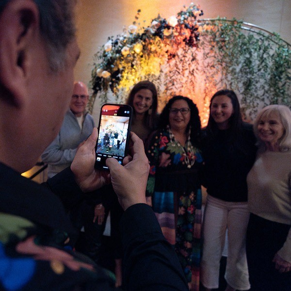 A guest taking photos of a group of attendees during the 2024 Celebration of First Foods Dinner.