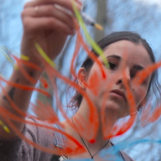 Teen with bi-polar disorder painting outside on glass. A close up.