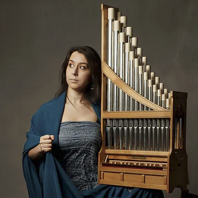 Catalina Vicens dressed in a peacock blue holding an organetto.
