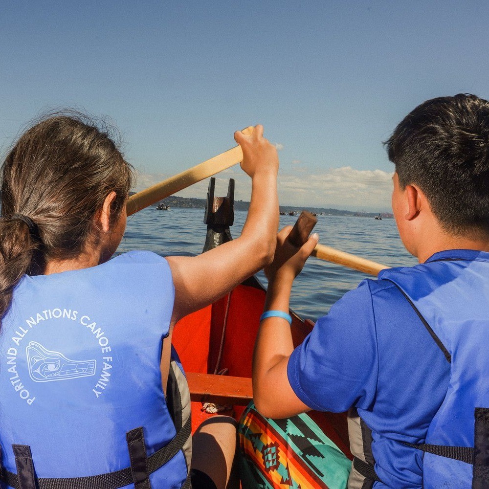 two people paddling a canoe on water