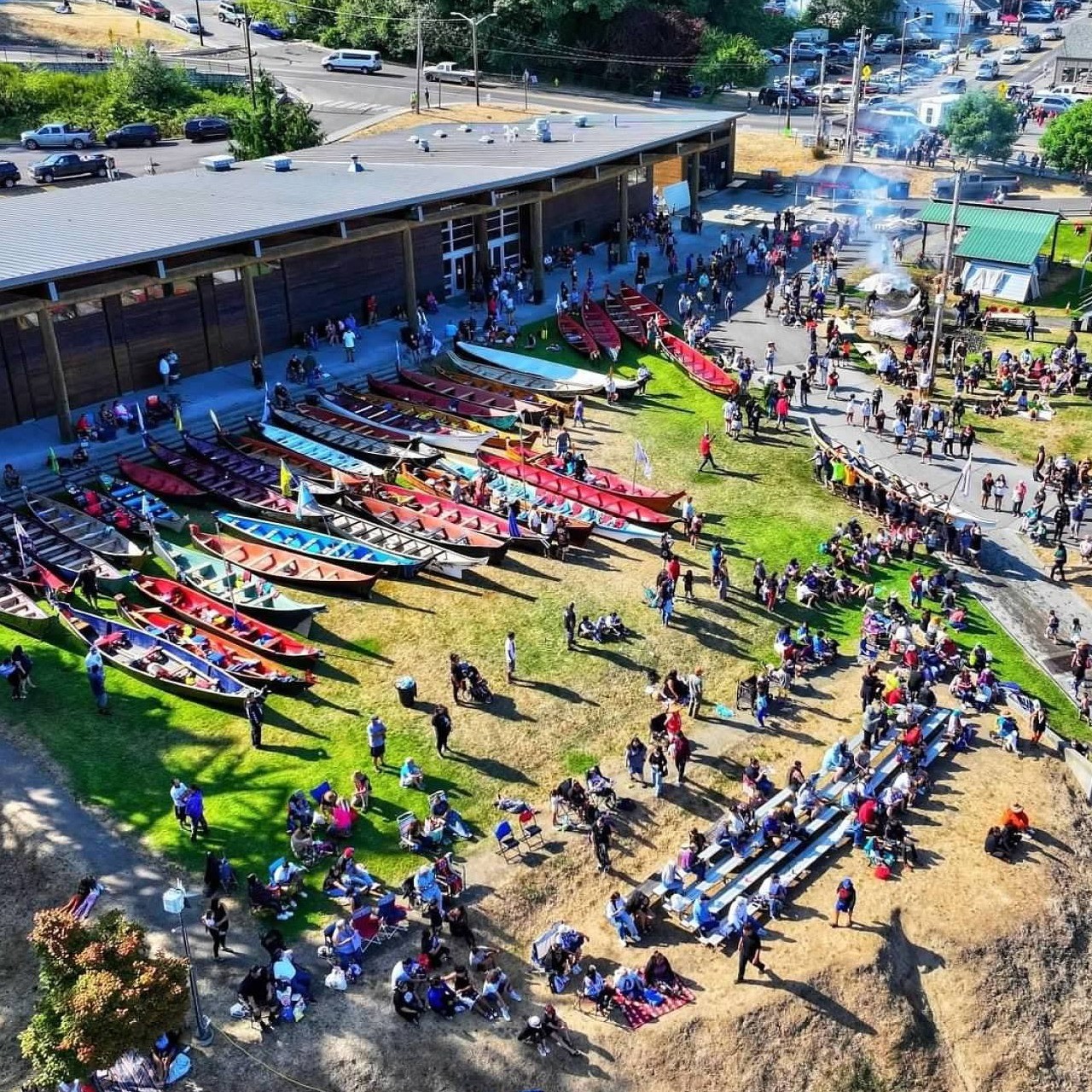 a crowd of people milling around lines of large canoes