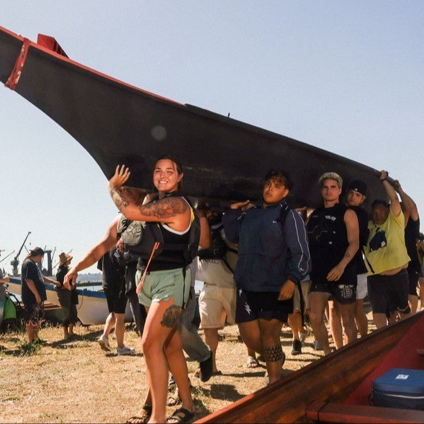a group of people carrying a large canoe