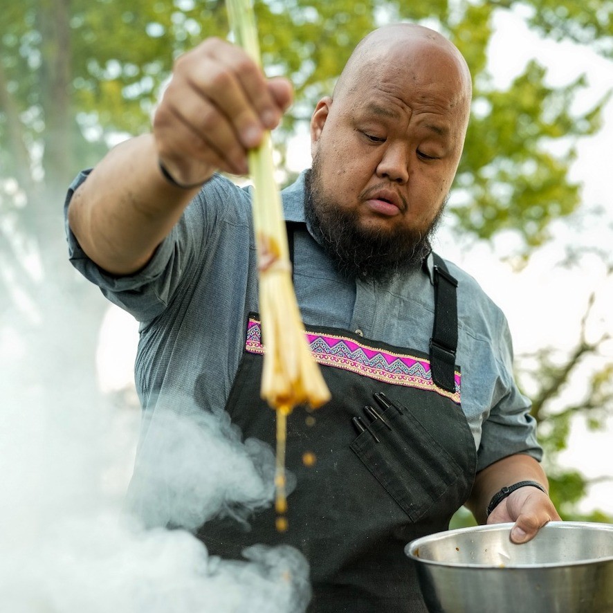 a chef adding ingredients from a bowl