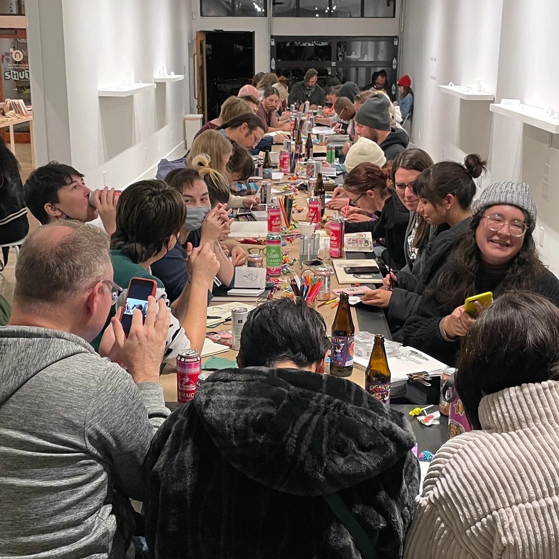 a table full of people drawing, socializing and drinking together