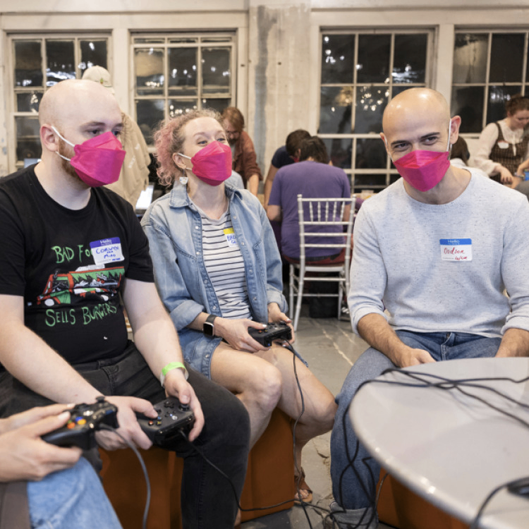 Several masked people playing a multiplayer indie game at a PIGSquad event