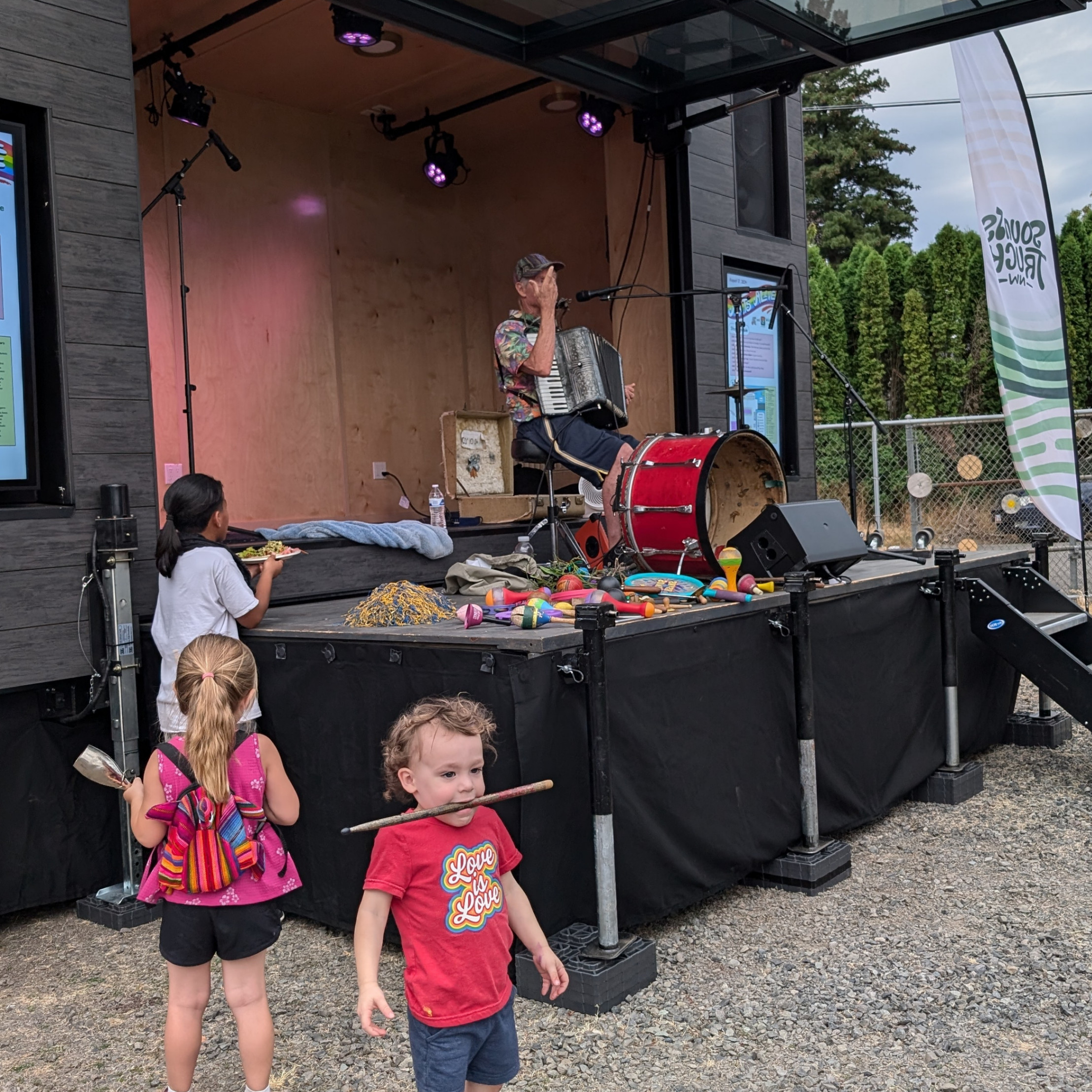 A musician with multiple kids around play on Sounds Truck NW stage.