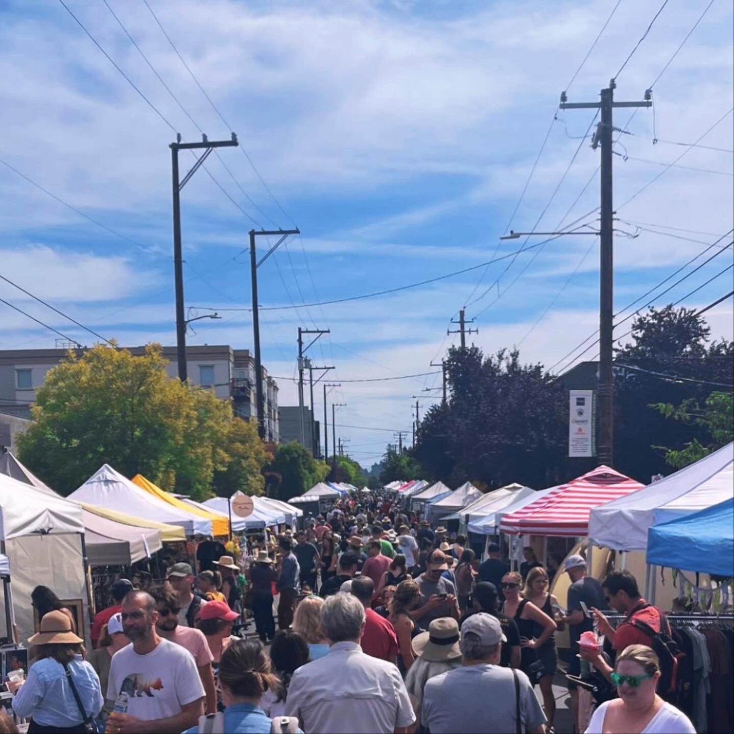 a crowd of people browse an outdoor street market