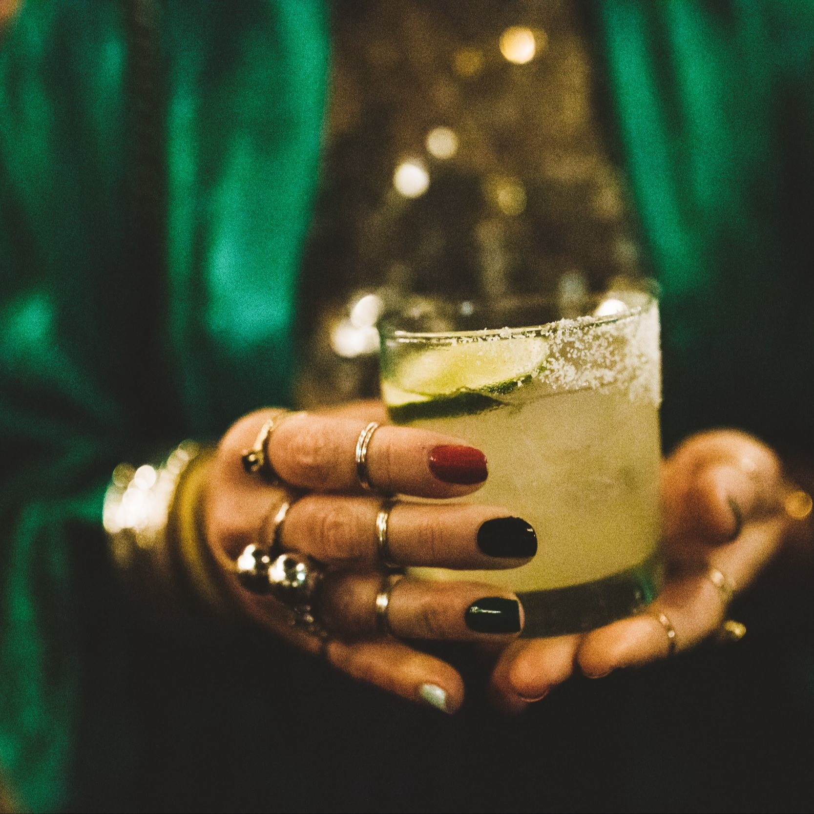 two hands holding a drink with salt on the rim