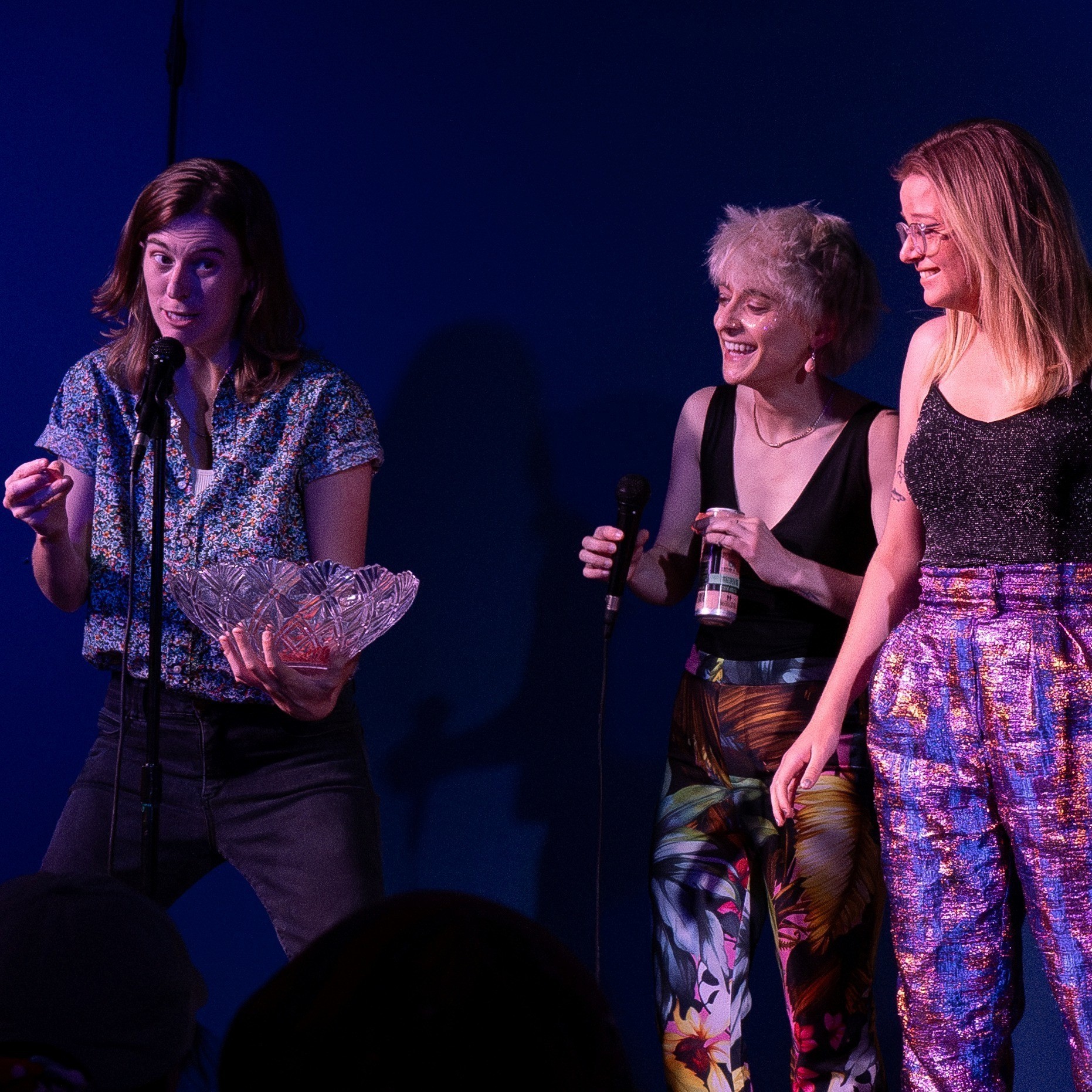 three people on stage, one with a microphone