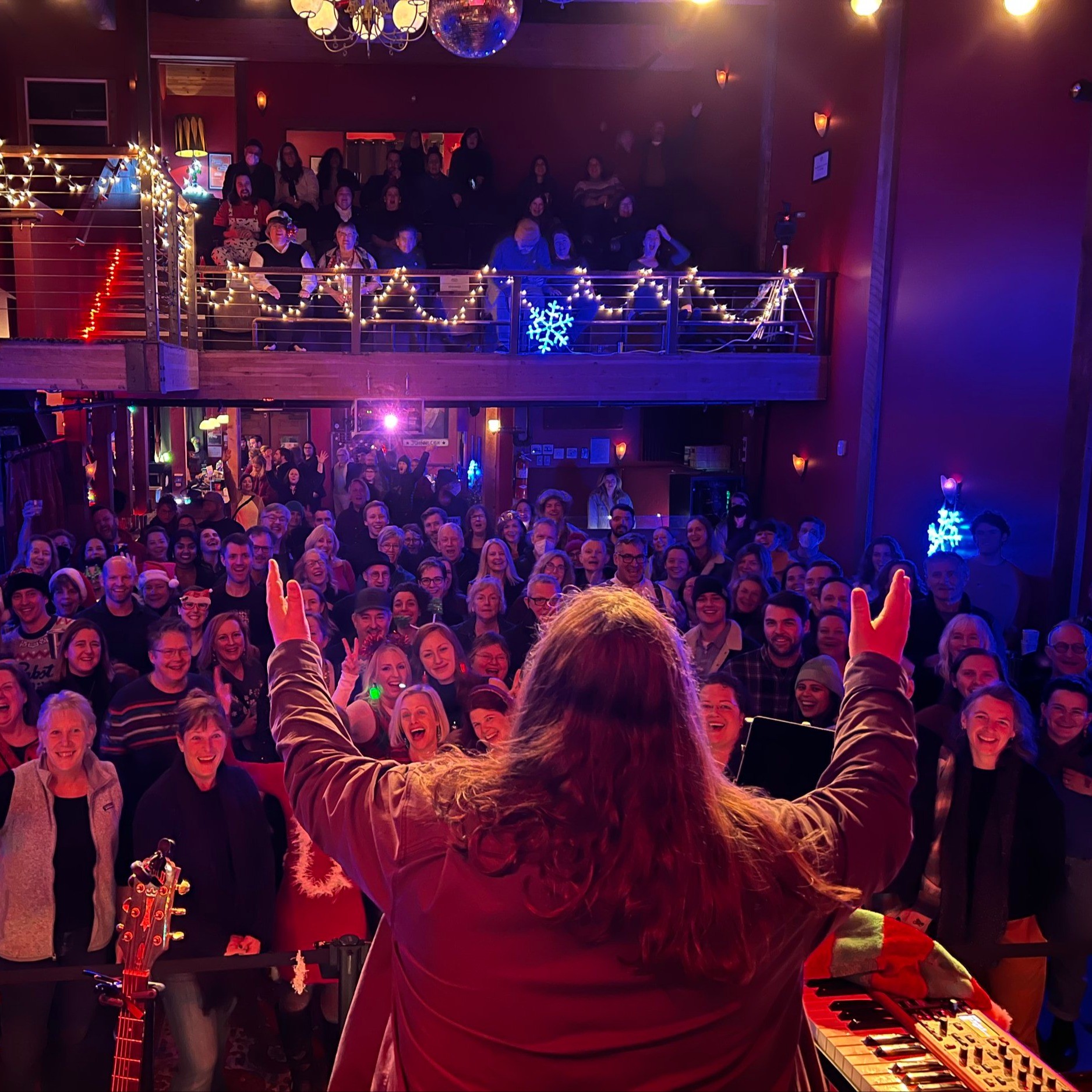 person on stage conducting singing crowd