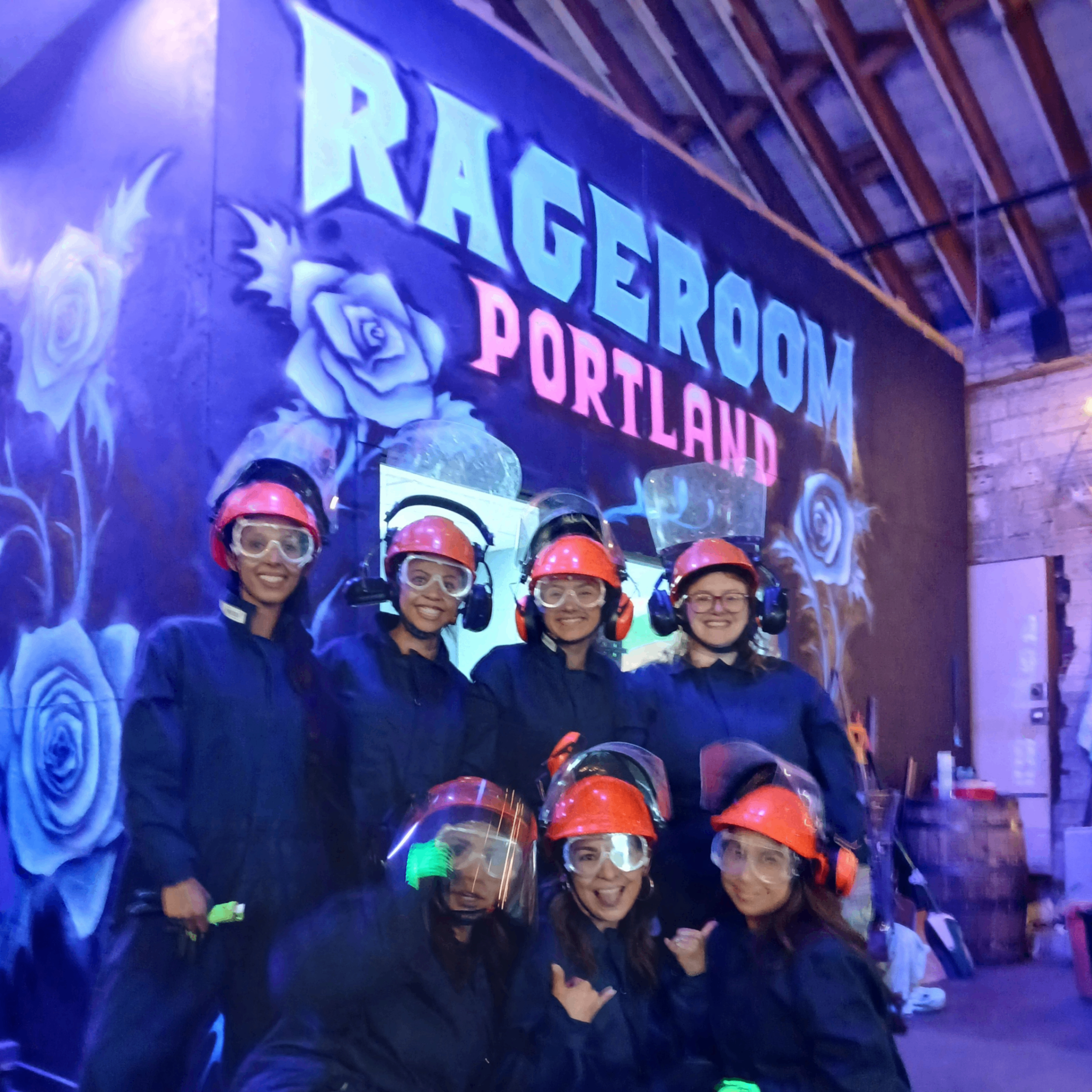 people wearing protective gear in front of a sign saying "rageroom Portland"