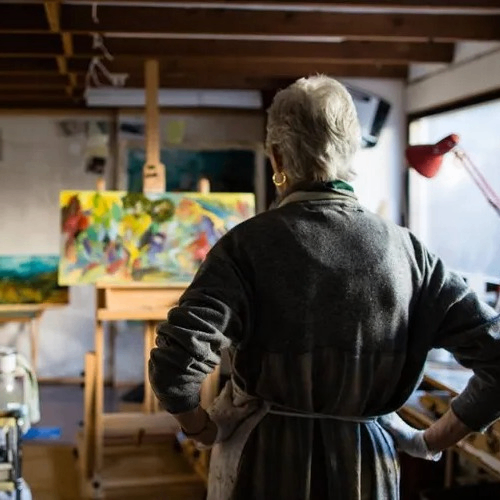 the back of a person looking at a painting on a easel