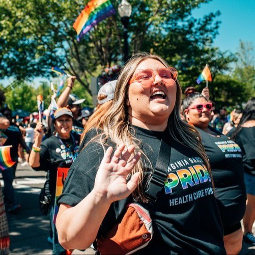 people walking in a pride parade waving to the onlookers