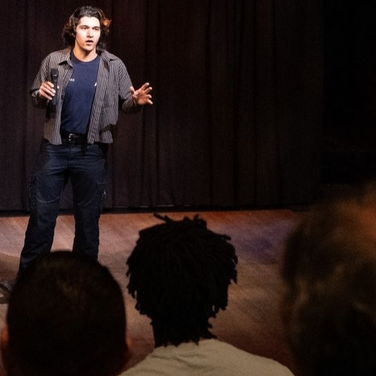 person with a microphone on stage in front of an audience