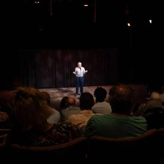 person with a microphone on stage in front of an audience