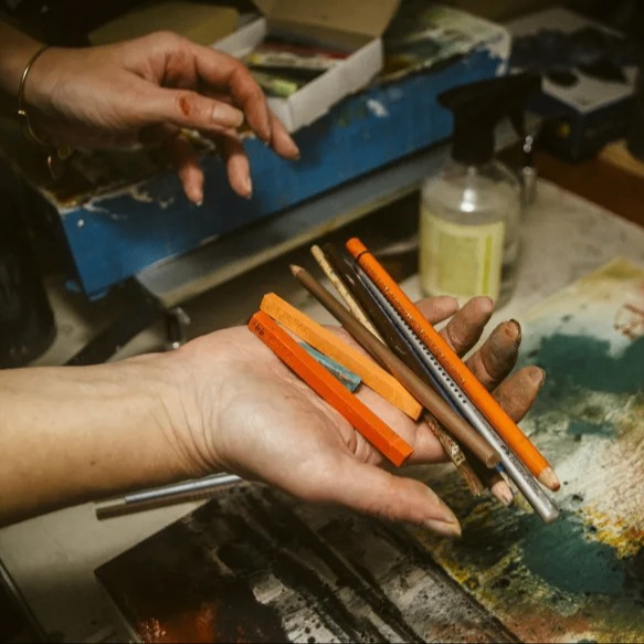 hands holding a variety of colored pencils