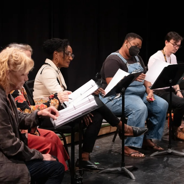 people sitting in front of music stands reading a play