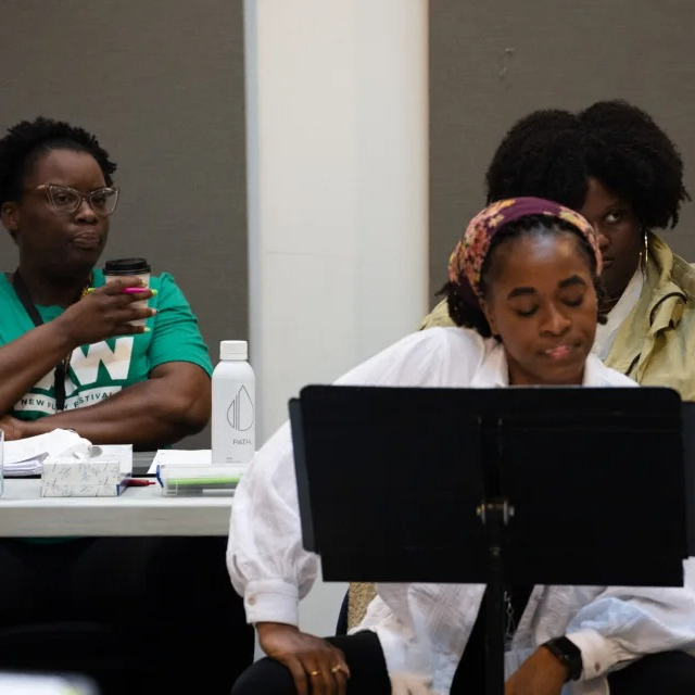 people sitting at tables reading a play