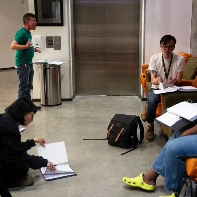 people rehearsing while reading pages of plays
