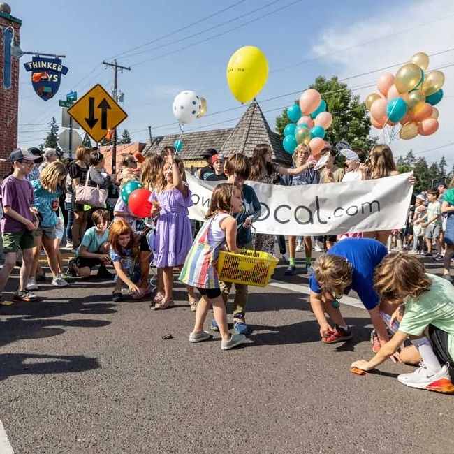kids bend to pick up candy thrown from a parade