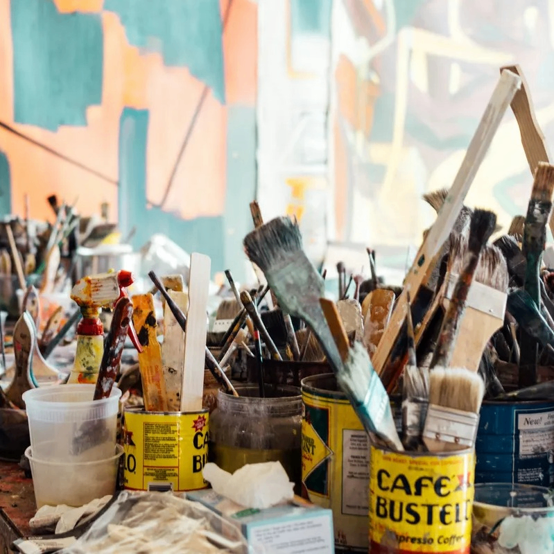 a collection of paintbrushes in cans