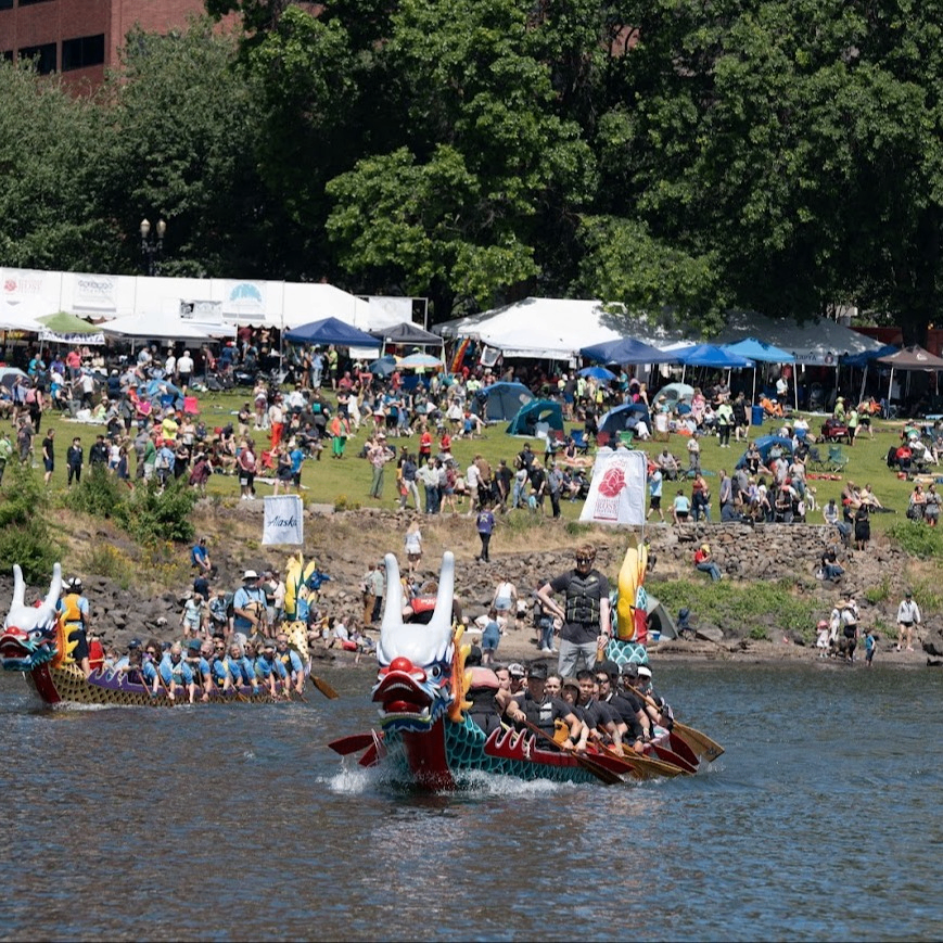crowds on shore watching dragonboats racing on a river