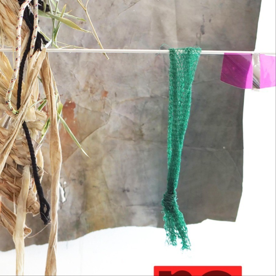 a piece of fabric and reeds hanging on a line