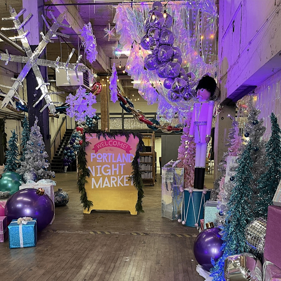 festive decorations surrounding a Portland Night Market welcome sign