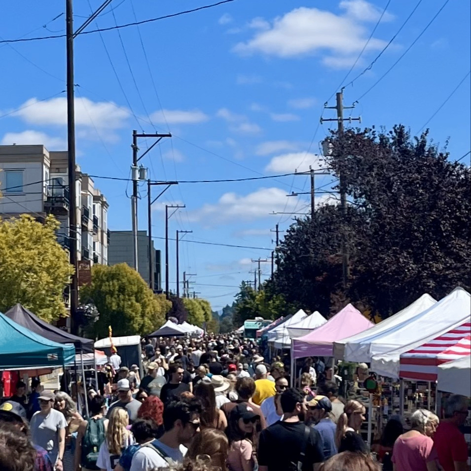 a crowd of people browse an outdoor street market